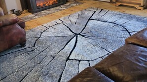 Ein rustikales Wohnzimmer mit Kamin, Ledersofas, einem großen Teppich und Holzmöbeln.