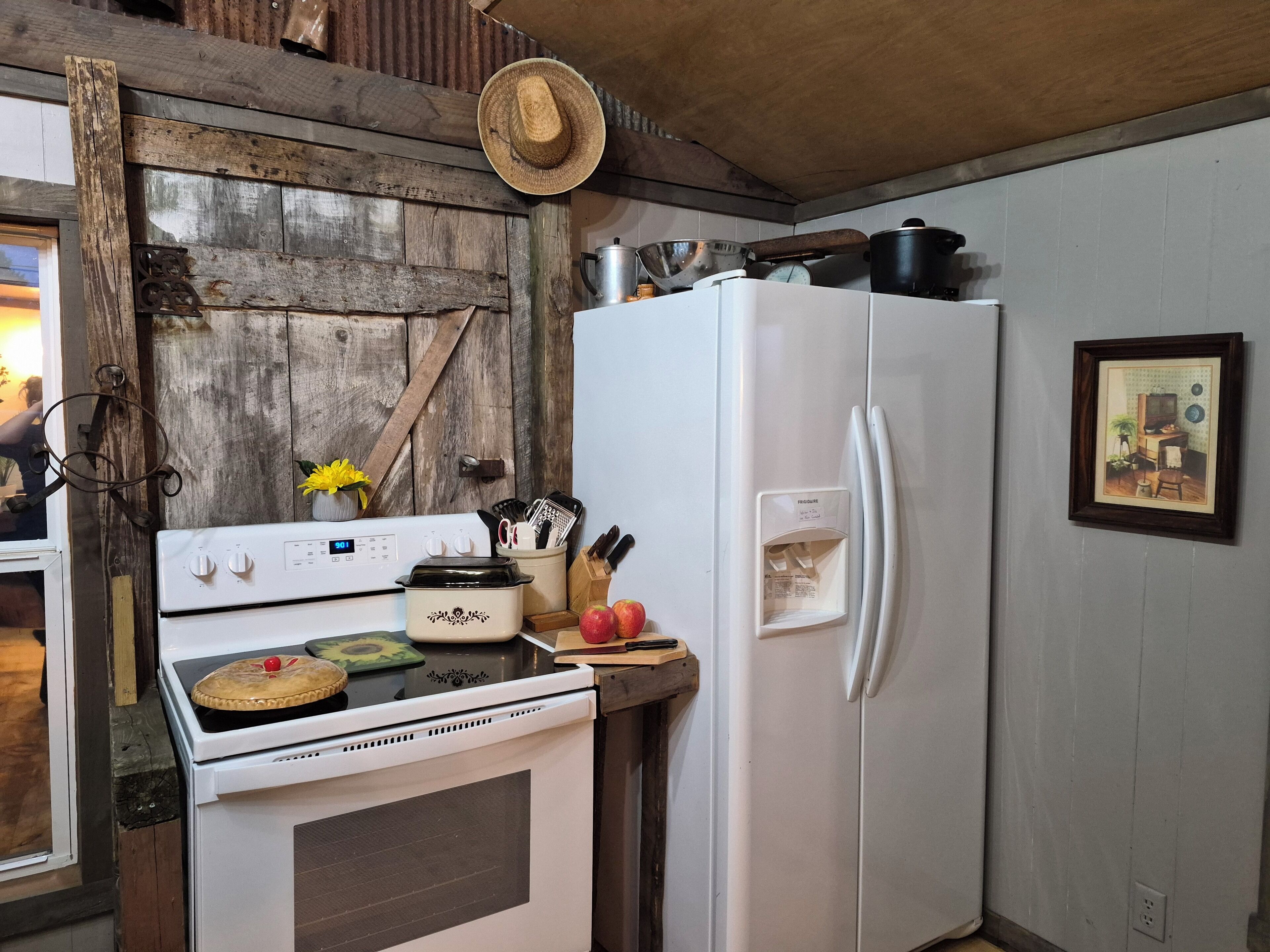 A kitchen with a white stove, a white refrigerator, and a wooden wall.