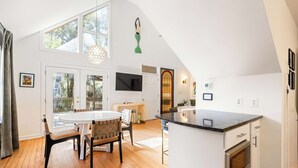 Een ruime keuken met een groot eiland, houten vloeren en een eethoek met een ronde tafel en stoelen.