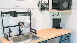 Una cocina con un fregadero, lavavajillas y microondas sobre una encimera de madera.