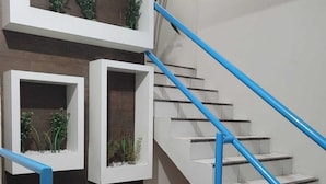 A modern staircase with blue handrails and white steps, flanked by white walls with built-in planters containing greenery. - Sol do Centro Pousada (Fortaleza)