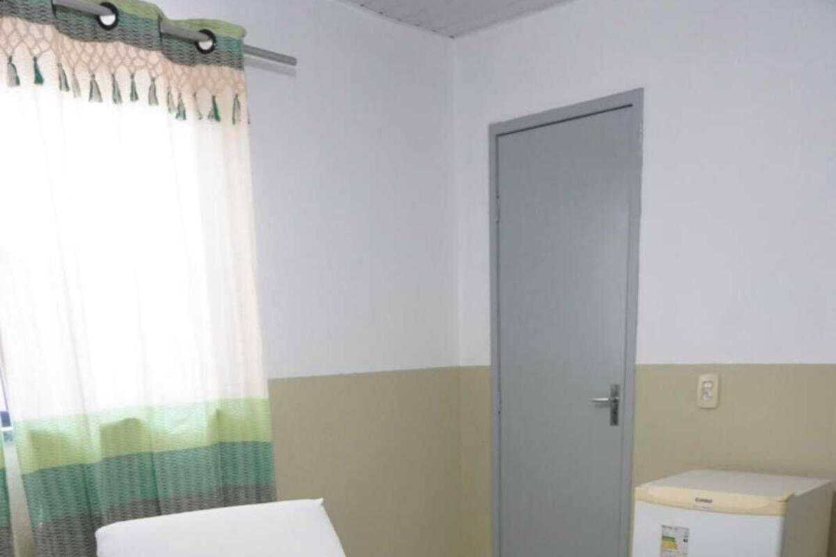Une chambre d’hôtel équipée d’un lit, d’une télécommande, d’une serviette et d’un petit réfrigérateur.