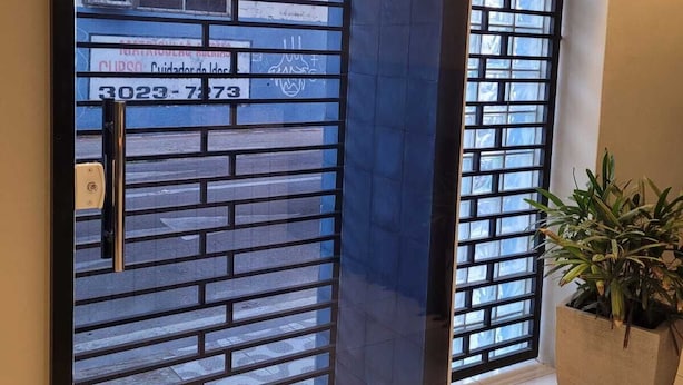 A reception area with a sign reading "SAÍDA" above a door with a metal grid pattern. - Sol do Centro Pousada (Fortaleza)