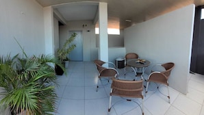 A covered outdoor area with a dining table and chairs, potted plants, and a door leading to an interior space. - Sol do Centro Pousada (Fortaleza)