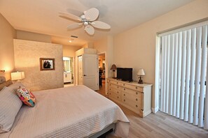 Ein Schlafzimmer mit Bett, Kommode, Fernseher und Deckenventilator.