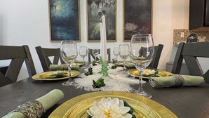 Een eettafel gedekt met gouden borden, witte servetten en heldere wijnglazen.