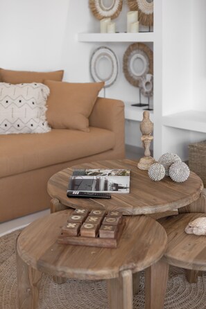 Ein gemütliches Wohnzimmer mit einer braunen Couch, einem Holztisch und einem kleinen Tisch mit einem Gesellschaftsspiel.