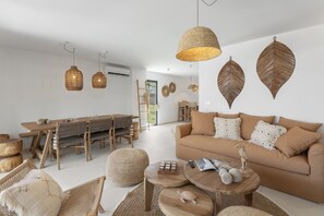 A modern living room with a sofa, coffee table, and dining area. - Villa Kaia (oyster pond)