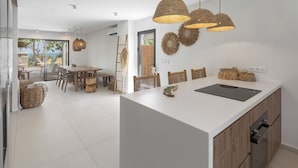Eine moderne Küche mit einer großen Kochinsel, Holzstühlen und gewobenen Leuchten.