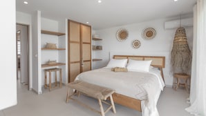 Ein Schlafzimmer mit einem hölzernen Bett, zwei Nachttischen, einer Bank, einem Kleiderschrank und Wanddekoration.