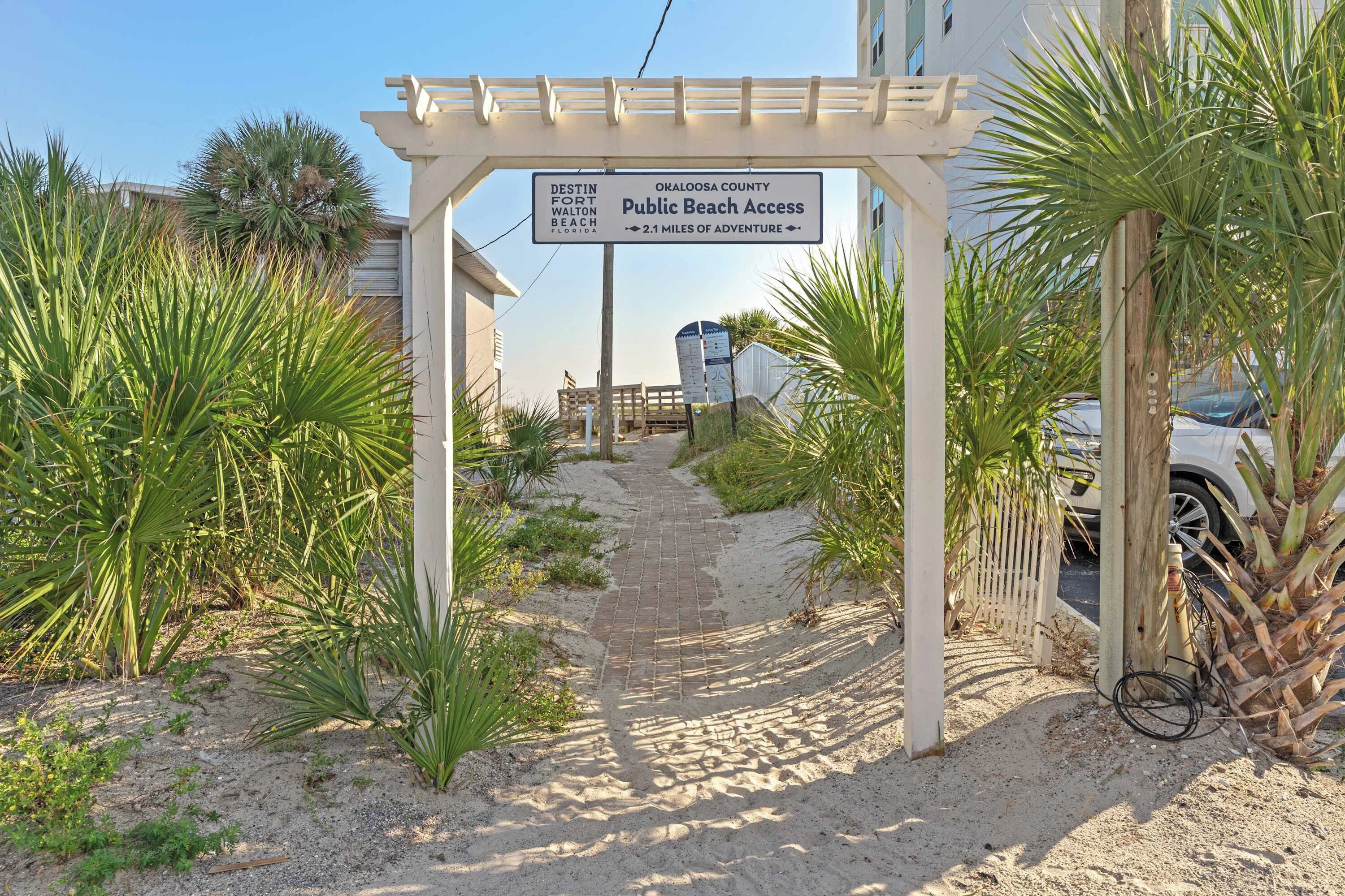 A pathway leading to a beach entrance with a sign indicating public beach access.