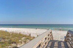 A wooden boardwalk leading to a sandy beach with clear blue water. - Tropical Isle 209🌴Beach Access👙 (Fort Walton Beach)