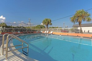 A swimming pool with a metal ladder, surrounded by a white fence, and palm trees in the background. - Tropical Isle 209🌴Beach Access👙 (Fort Walton Beach)