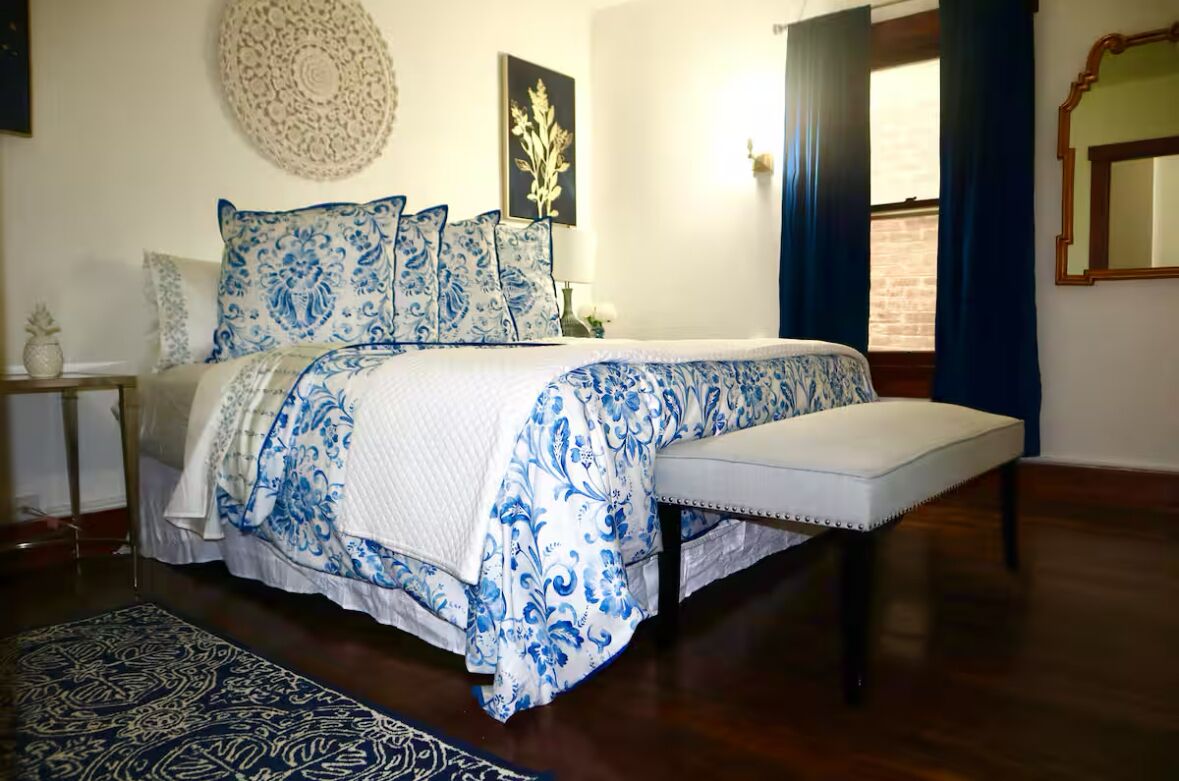 Une chambre à coucher avec un grand lit, un banc et un tapis à motifs.