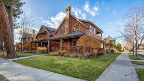 A large, two-story house with a prominent chimney, a covered porch, and a well-maintained lawn. - Pine Haven Retreat | Walk to Downtown & Pool (Sisters)