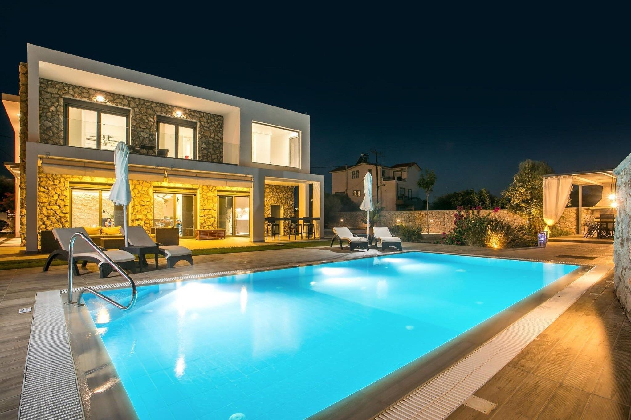 A modern pool area with lounge chairs and a stone facade building.