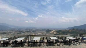 A terrace with tables and chairs overlooking a cityscape.