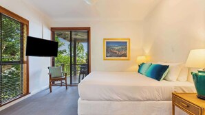 A hotel room with a bed, a television, a chair, a painting, and a window with blinds. - Vistas @ The Point Su (Port Douglas)