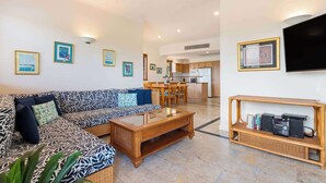 A spacious living area with a sofa, coffee table, and a console table with speakers. - Vistas @ The Point Su (Port Douglas)