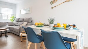 Ett modernt vardagsrum med en grå soffa, ett matbord med stolar och en plats för frukost.