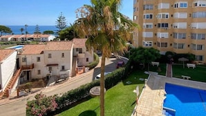Un immeuble résidentiel doté d’une piscine, d’un palmier et offrant une vue sur la mer.