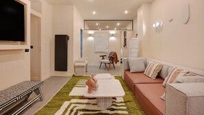 A modern living room with a sofa, a coffee table, a TV, and a patterned rug. - Marais Rue Archives next to Picasso Museum, Place des Vosges,and Rue de Bretagne (Paris)