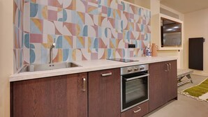 A modern kitchen with a colorful abstract backsplash, a double sink, a built-in oven, and wooden cabinets. - Marais Rue Archives next to Picasso Museum, Place des Vosges,and Rue de Bretagne (Paris)