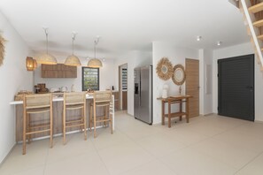 Eine moderne Küche mit einer zentralen Kochinsel, Barhocker und einem Kühlschrank.