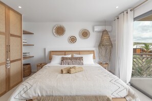 A bedroom with a large bed, a wooden wardrobe, and a balcony with a view. - Villa Tonka (Oyster Pond)