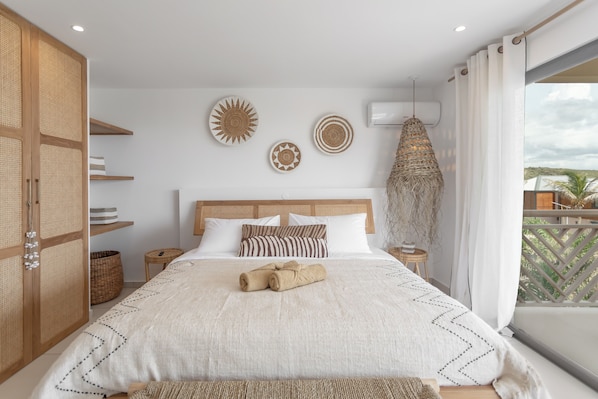 Een slaapkamer met een groot bed, een houten garderobe en een balkon met uitzicht.