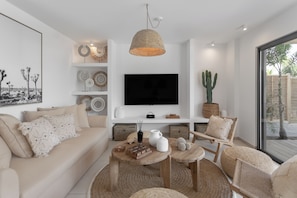 Een moderne woonkamer met een flatscreen televisie, een geweven lamp en een cactus.