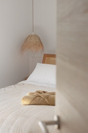 Ein Schlafzimmer mit einem Bett, einer Pendelleuchte und einem Holzkopfende.
