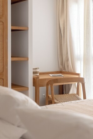 A bedroom with a wooden desk, a wicker chair, a bed, and a white wall. - Villa Tonka (Oyster Pond)