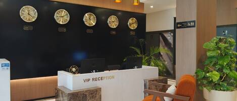 A reception area with a VIP reception desk, multiple wall clocks, and a seating area with a plant.