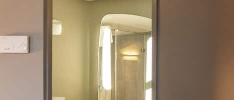 A modern bathroom with a toilet, sink, and mirror.