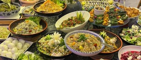 Un despliegue de comida tipo buffet con diversos platos y un comedor al fondo.