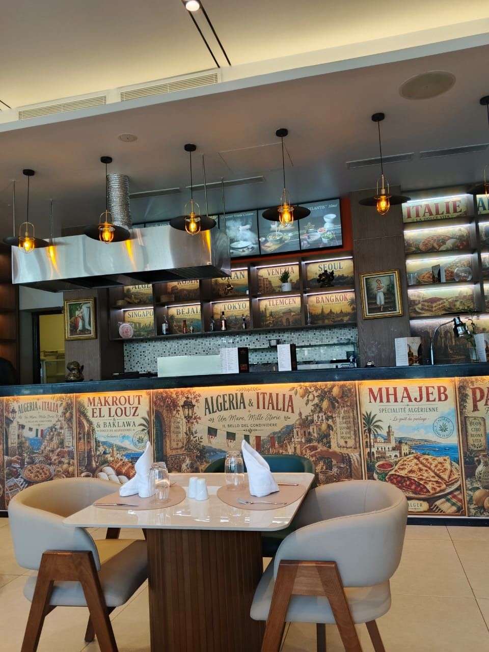 Ein Restaurantinneres mit Barbereich, Sitzgelegenheiten und einem Wandbild, das verschiedene Orte zeigt.