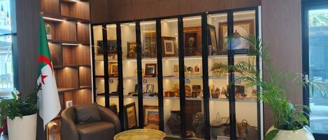 A lobby with a seating area, a display of decorative items, and a flag.