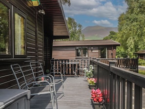 A wooden cabin with a deck, outdoor seating, and a view of a mountain. - Watendlath (Keswick)