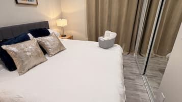 Ein Hotelzimmer mit einem großen Bett, einem Nachttisch mit Lampe, einer Wand-Klimaanlage und einer Glastür mit Vorhängen.