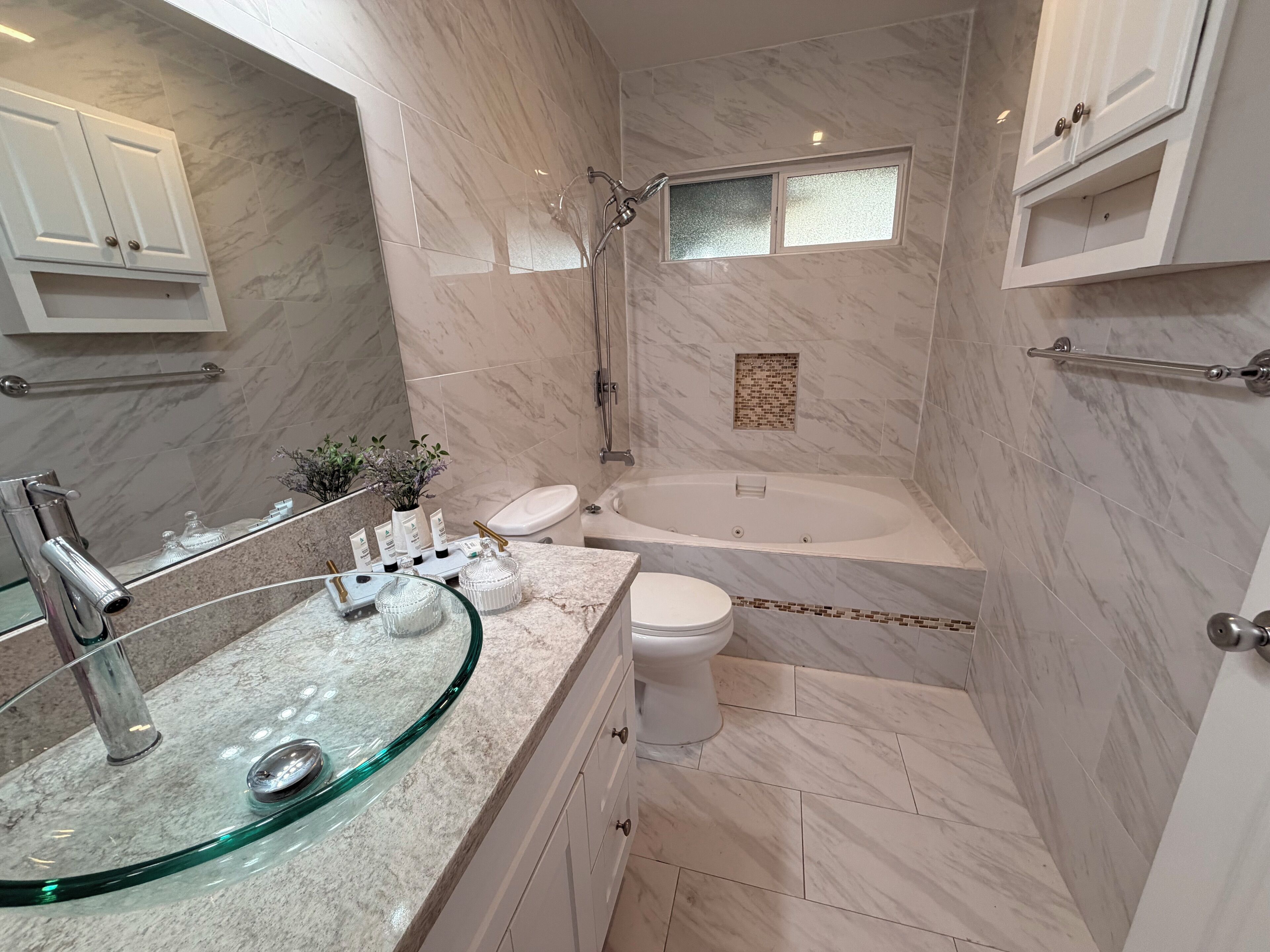 Ein modernes Badezimmer mit Waschbecken aus Glas, einer Badewanne und einer Dusche.