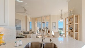 Cozinha moderna com uma pia dupla, área de jantar com vista e sala de estar com sofá e mesa de centro.