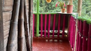 A covered outdoor area with a red floor, bamboo pillars, and a green railing. - Cabañas el Portal (Santa Rosa de Cabal)