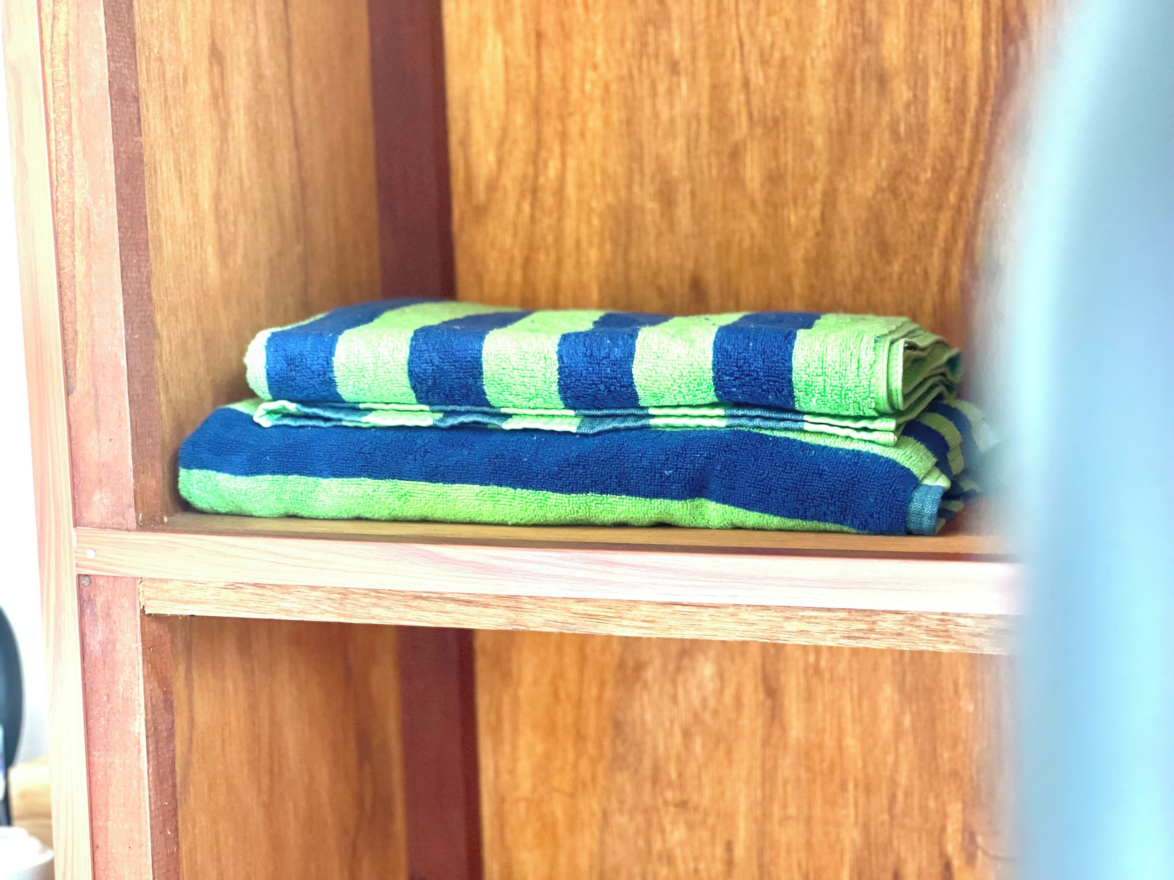 A wooden shelf with folded towels.