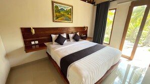 A large bed with a wooden headboard, a nightstand, a painting, and a view of greenery through a window. - The Lebah Kelingking Villa (Penida Island)