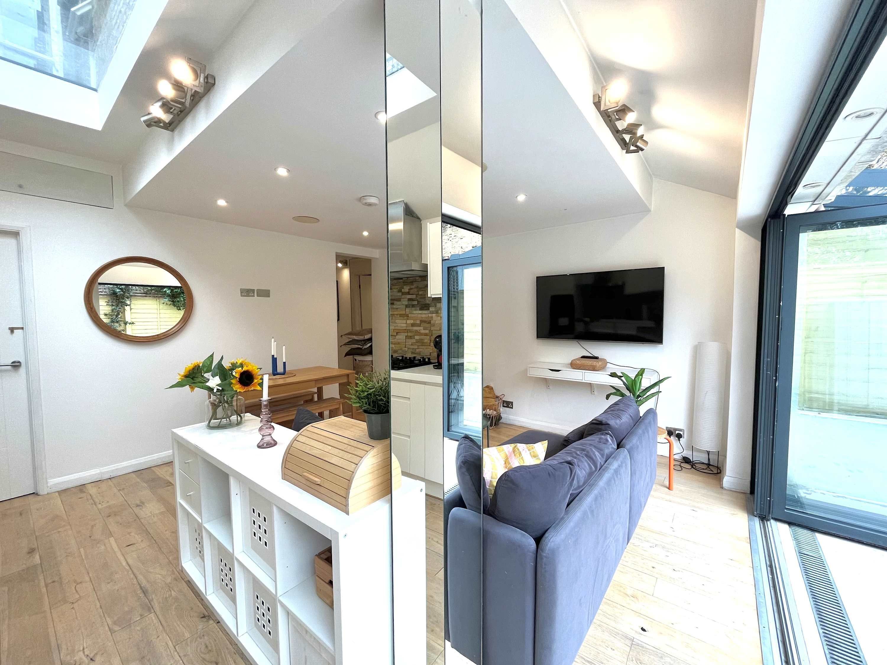 A modern living room with a sofa, a TV, and a dining area with a table and chairs.