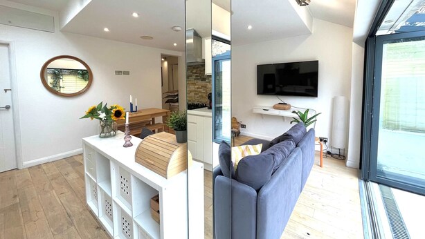 Uma sala de estar moderna com sofá, televisão e área de refeições com mesa e cadeiras.