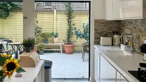 Uma cozinha moderna com uma ilha grande, uma área de jantar com bancos e vista para o jardim externo.