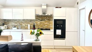 Cozinha moderna com armários brancos, painel de backsplash de pedra, forno Bosch e pia.