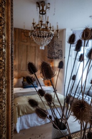 Ein Schlafzimmer mit einem Bett, einer Chandelüster und getrockneten Blumen in einer Vase.